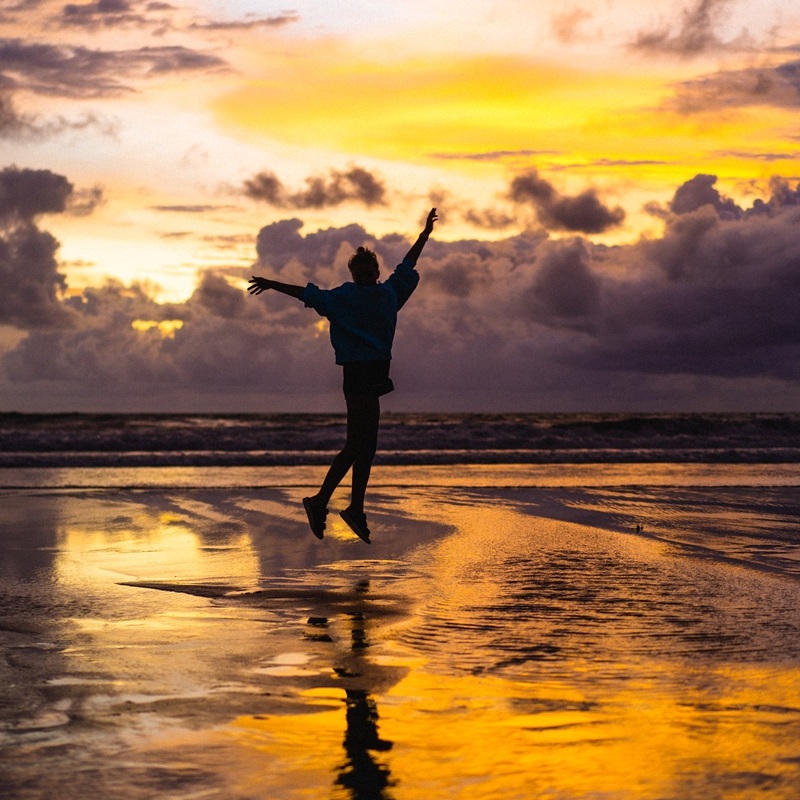 Beautiful young woman at sunset on the ocean, Bali, Indonesia.
